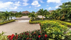 A residential area with houses, a paved driveway, and well-maintained gardens with various plants and flowers. - I Heart JA  Coastal DreamVIlla-Richmond Estates (St. Ann's Bay)