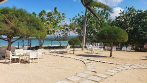 A beachside area with outdoor seating and a paved walkway. - I Heart JA  Coastal DreamVIlla-Richmond Estates (St. Ann's Bay)