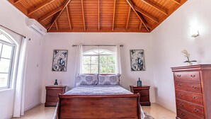 Ein Schlafzimmer mit Holzboden, einem Bett, zwei Nachttischen, einer Kommode und zwei gerahmten Bildern an den Wänden.