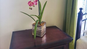 A potted orchid on a wooden table against a wall. - I Heart JA Fairway (Kingston)