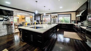 A modern kitchen with a large island, dark wood flooring, and a stone accent wall.