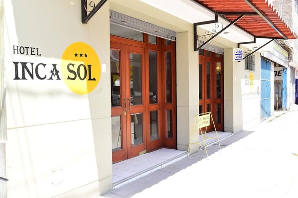 A hotel entrance with a sign reading "HOTEL INCA SOL" and a yellow sign indicating a reception area.