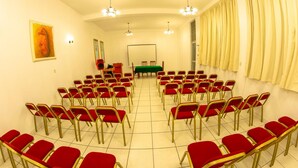 A conference room with rows of red chairs, a green table, and a whiteboard. - Hotel Incasol (Jesús Nazareno)