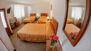 A hotel room with two beds, a mirror, a nightstand, a lamp, and a vase with flowers. - Hotel Incasol (Jesús Nazareno)