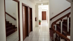 A hallway with wooden doors, a staircase, and a potted plant. - Hotel Incasol (Jesús Nazareno)