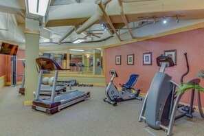 Un gimnasio con cintas de correr, una máquina elíptica y una bicicleta estática.