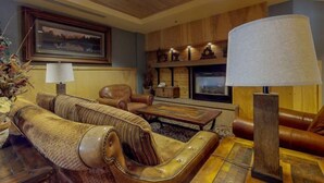 A cozy living room with leather furniture, a wooden ceiling, and a framed landscape painting. - 1 Bedroom Mountain Condo in River Run Village with Beautiful Mountain Views and Walking Distance to Ski (Keystone)
