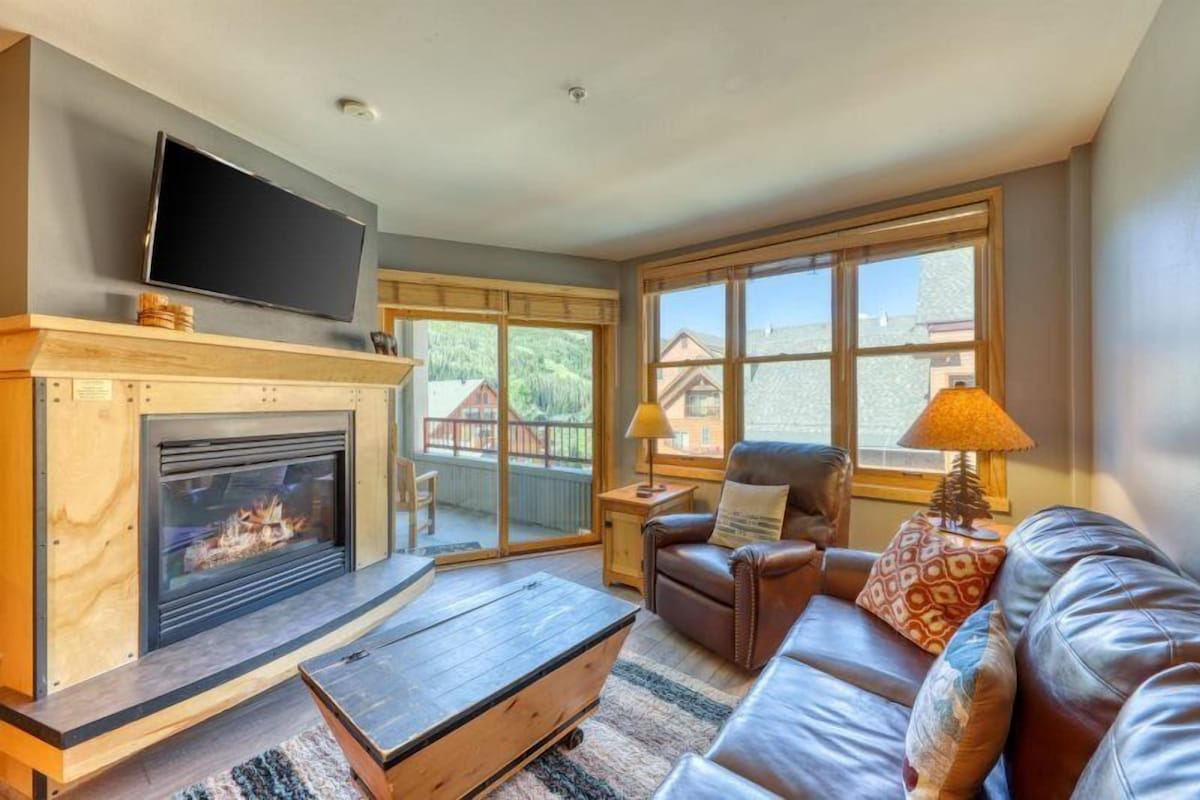 Una sala de estar con chimenea, sofá de cuero y televisor.