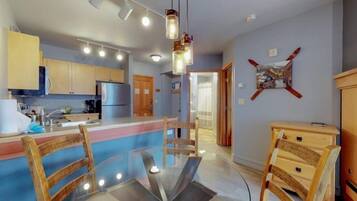 Una cocina moderna con armarios de madera, una mesa de comedor de vidrio e iluminación colgante.