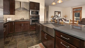 A modern kitchen with dark wood cabinets, stainless steel appliances, and a large island. - Premier 2 Bedroom Ski in, Ski out Lone Eagle Condo With the Best Access to Skiing in Keystone (Keystone)