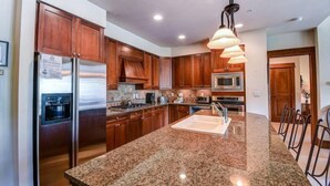 A kitchen with wooden cabinets, stainless steel appliances, granite countertops, and pendant lighting. - Premier 4 Bedroom Ski in, Ski out Lone Eagle Condo With the Best Access to Skiing in Keystone (Keystone)