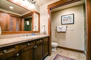 A bathroom with a wooden vanity, a large mirror, a sink, and a toilet. - Premier 4 Bedroom Ski in, Ski out Lone Eagle Condo With the Best Access to Skiing in Keystone (Keystone)