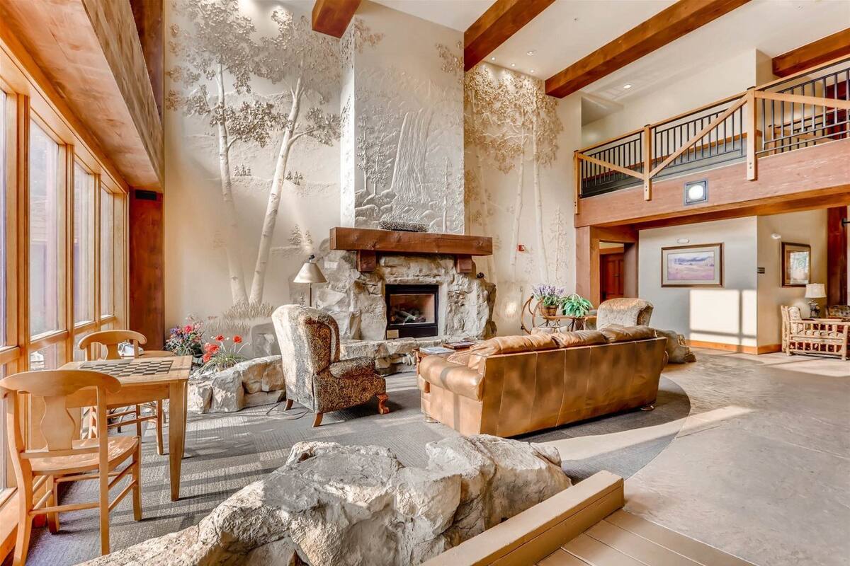 A spacious living area with a fireplace, wooden furniture, and a stone accent wall.