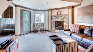 A spacious living room with a fireplace, a sofa, a coffee table, and a TV. - 4 Bedroom Ski in, Ski out Mountain Vacation Rental Located Next to Historic Main Street in Downtown Breckenridge (Breckenridge)