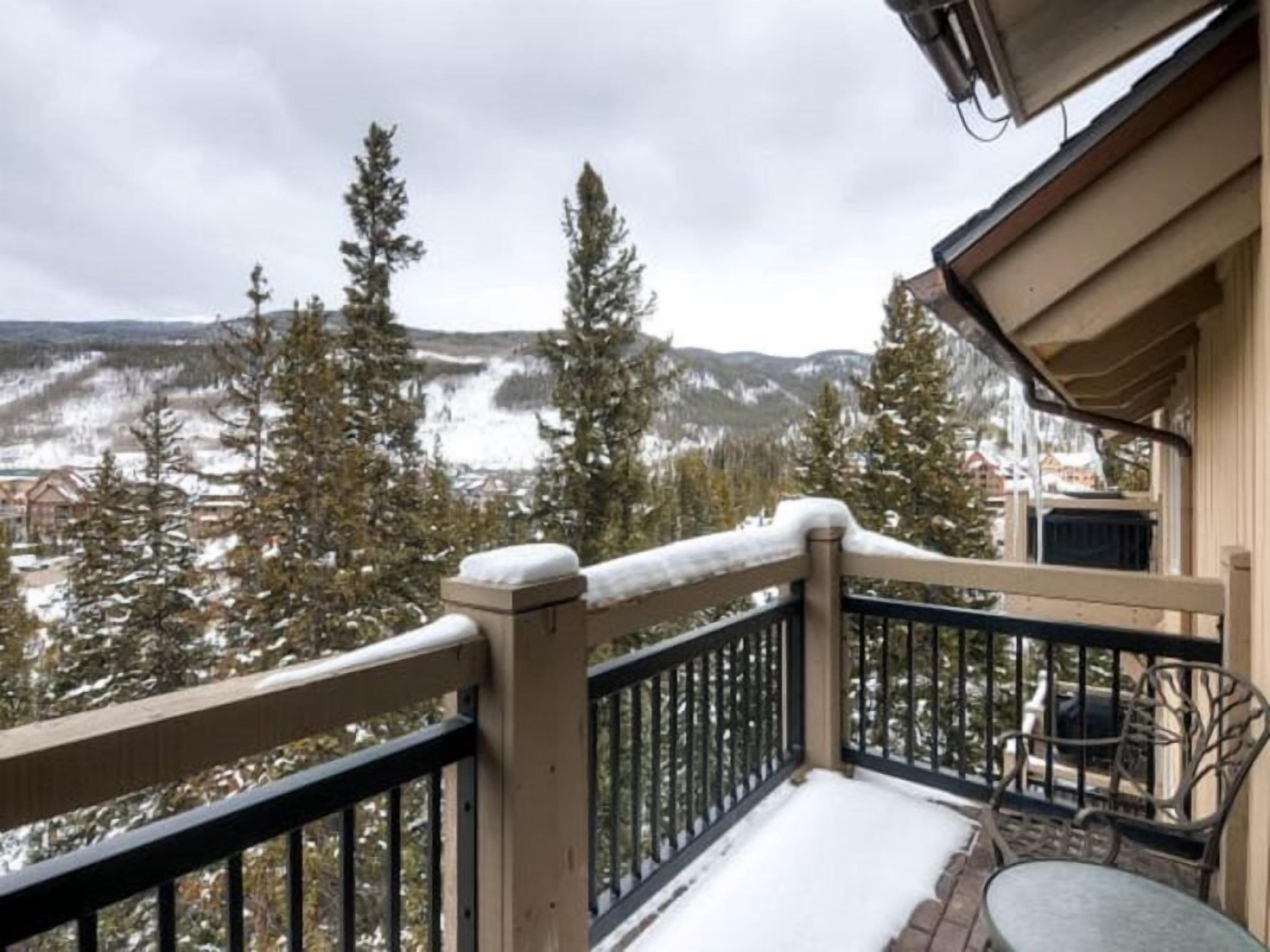 A balcony with a view of snow-covered mountains and trees.
