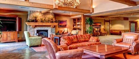 A spacious living area with a fireplace, leather sofas, a large wooden coffee table, and a chandelier.