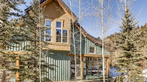 A log cabin with a steeply pitched roof, a front porch, and a large window. - Family Friendly 3 Bedroom Mountain Vacation Rental in Keystone With Complimentary Shuttle Service and Hot Tub Access (Keystone)