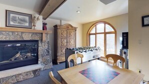 Una sala de estar acogedora con chimenea de piedra, una mesa de fútbol y un ventanal grande.