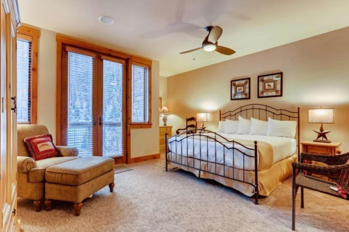 A bedroom with a bed, a chair, a desk, and a ceiling fan.