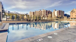 A swimming pool with lounge chairs and a view of mountain buildings.