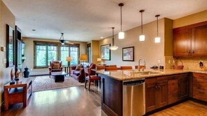 A spacious kitchen with a central island, wooden cabinets, pendant lighting, and a large window providing natural light.