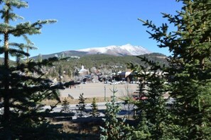 A town with a mountain in the background, a parking lot, and trees in the foreground. - Luxury 2 Bedroom Mountain Vacation Rental in Breckenridge With Access to a Hot Tub and Heated Garage Parking (Breckenridge)