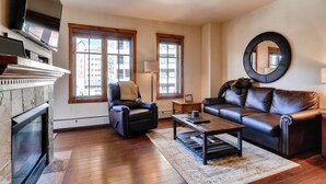 A living room with a fireplace, leather sofa, armchair, coffee table, and a large mirror on the wall.