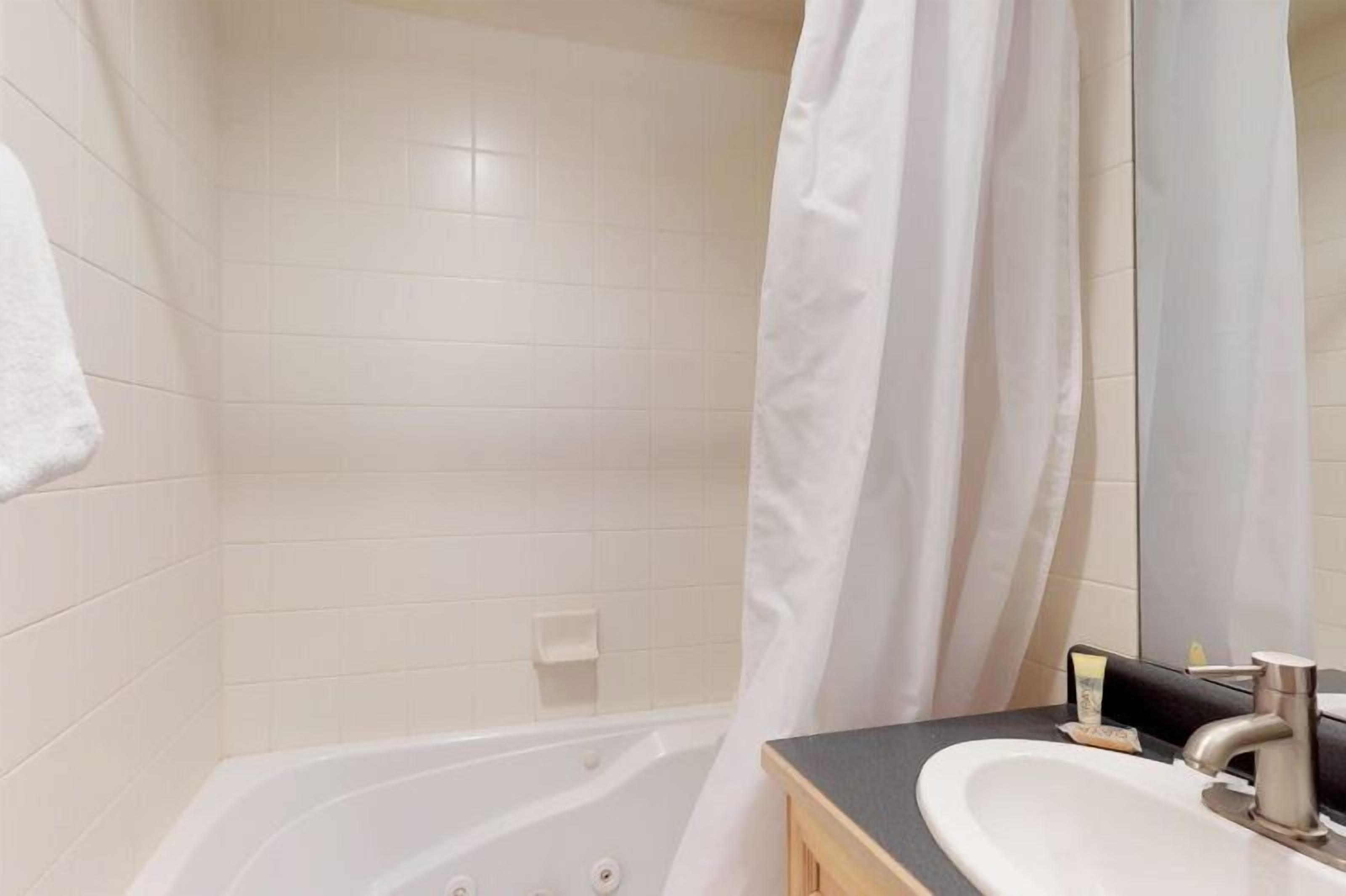 A bathroom with a bathtub, a sink, and a mirror.