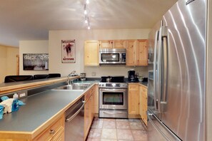 Enjoy cooking in this well-equipped kitchen with a double sink, microwave, oven, and refrigerator.