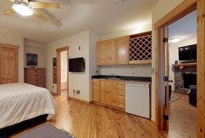 Cozy retreat with a single bed, kitchenette, and stone fireplace.