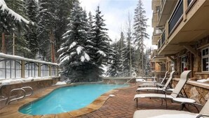 Zona de piscina con sillones de descanso y un árbol cubierto de nieve.