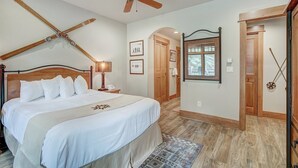 Un dormitorio con una cama grande, cabecera de madera, ventilador de techo y ventana con vistas al exterior.
