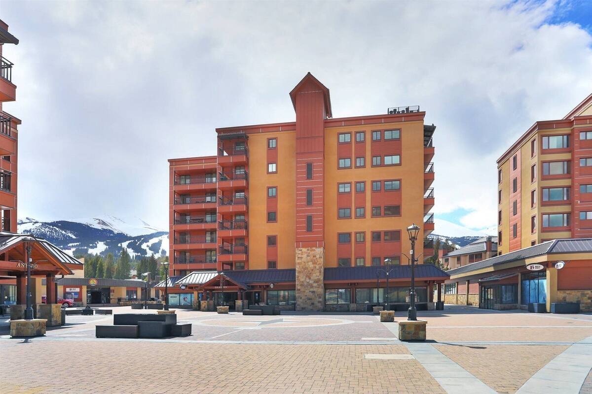 A multi-story hotel with a central courtyard, featuring a stone fountain and outdoor seating areas.