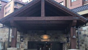 A hotel entrance with a stone facade, a wooden overhang, and a sign indicating guest reception. - 1 Bedroom Ski in, Ski out Mountain Vacation Rental Located Next to Historic Main Street in Downtown Breckenridge (Breckenridge)