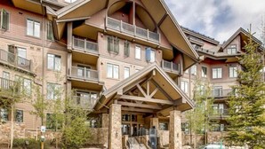 A multi-story hotel with a stone facade, balconies, and a covered entrance area.