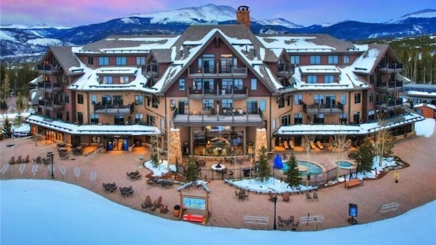 A large, multi-story hotel with a central courtyard, outdoor seating, and a pool.