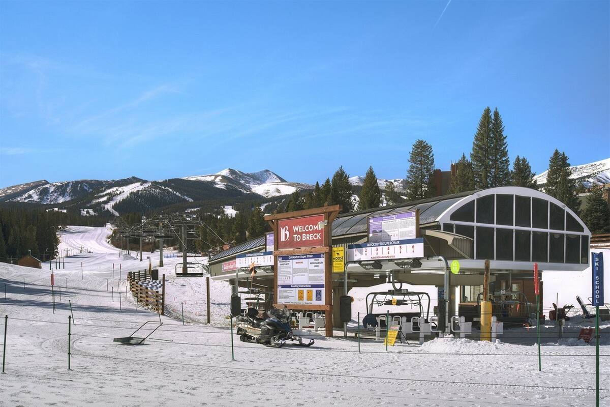 A ski resort with a sign welcoming visitors to Breck, a ski school, and a quicksilver superchair rental.
