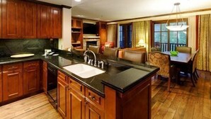 Una cocina amplia con armarios de madera, una isla central con lavamanos y una zona de comedor con mesa y sillas.