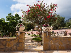 A stone pathway leading to a building entrance, with two stone baskets on pedestals.