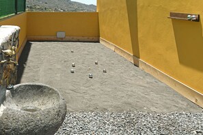 A rooftop terrace with a yellow wall, a stone basin, and a metal railing.