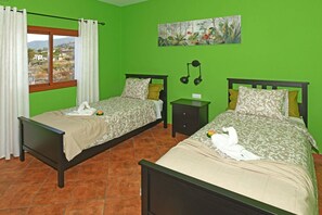 A room with two beds, a nightstand, a lamp, and a painting on the wall. - Villa Mica inTijarafe (Tijarafe)