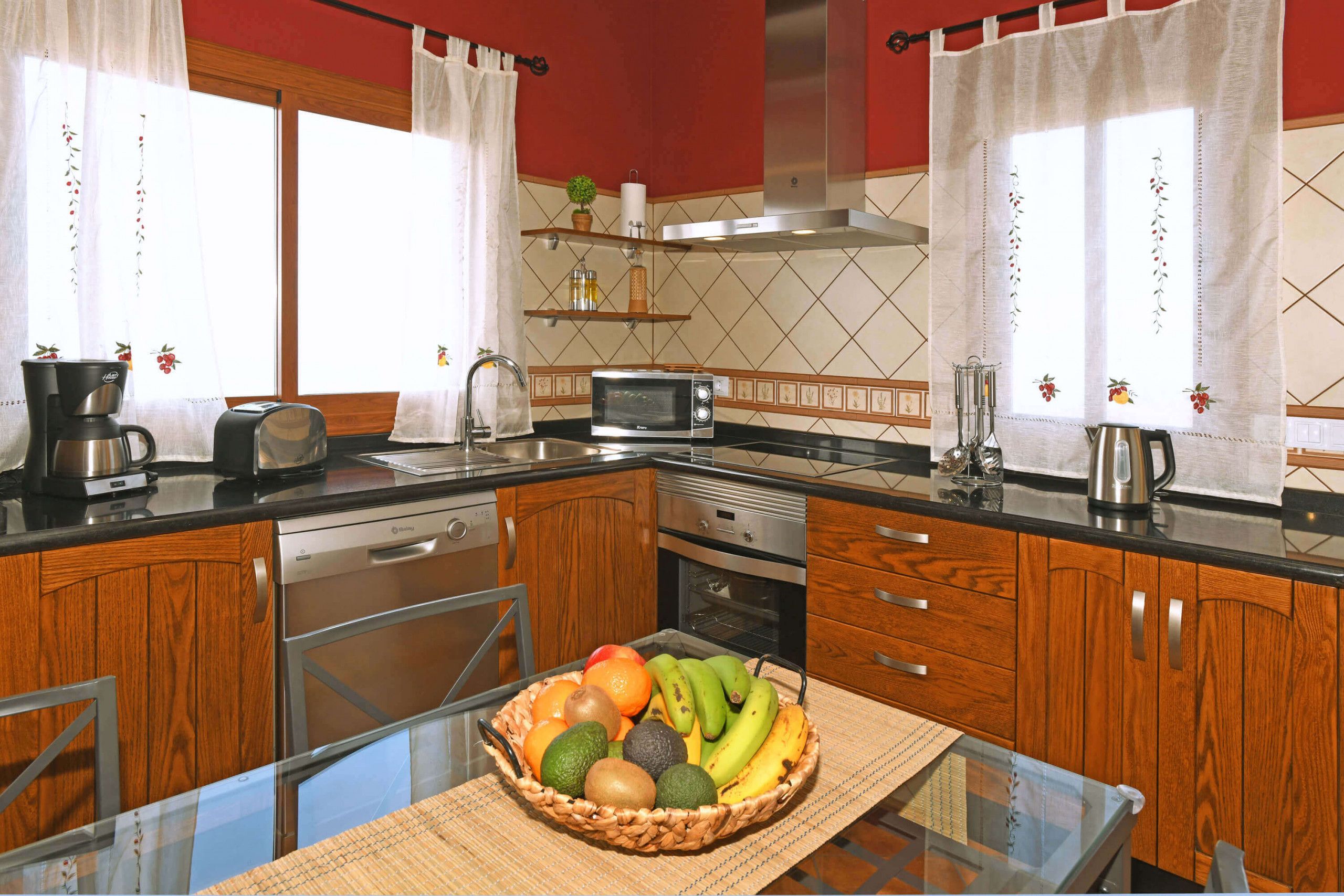 A kitchen with wooden cabinets, a microwave, a coffee maker, and a fruit basket on the counter.