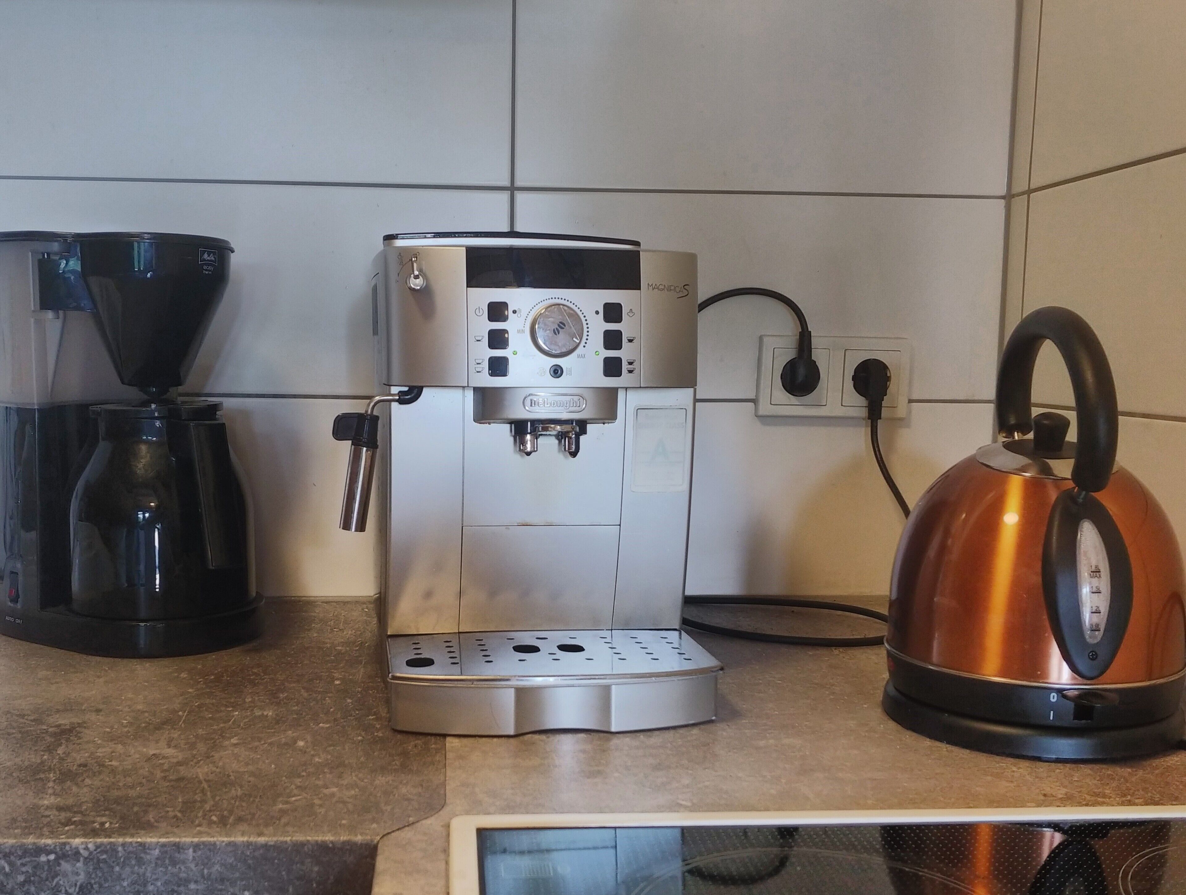 A kitchen with a coffee maker, a kettle, and a coffee grinder.
