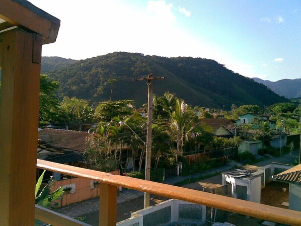 Un barrio residencial con casas, una montaña al fondo y un balcón con barandilla de madera.