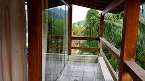A balcony with a view of lush greenery and mountains. - 4 suites WITH AIR CONDITIONING + 1 bedroom-living room with bathroom 2 refrigerators barbecue garden terrace TV DVD YT (São Sebastião)