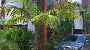 A vehicle parked in front of a building with a tiled roof and large windows. - 4 suites WITH AIR CONDITIONING + 1 bedroom-living room with bathroom 2 refrigerators barbecue garden terrace TV DVD YT (São Sebastião)