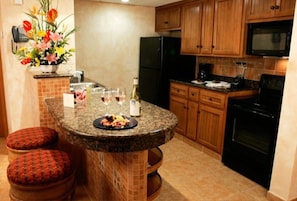 Enjoy cooking in this well-equipped kitchen with a central island, stove, refrigerator, and microwave.