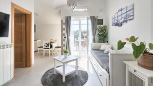 En moderne stue med sofa, sofabord og spiseområde med stole.
