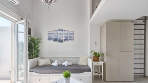 Et moderne, lyst værelse med en seng, et lille bord med en plante og et billede på væggen.