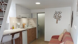 A compact living space with a kitchenette, a sofa, and a dining area. - Evans House II One Bedroom Maisonette (Chania)